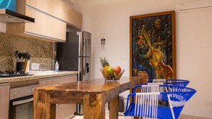 Une cuisine moderne avec une table à manger en bois, un panier de fruits et un tableau accroché au mur.