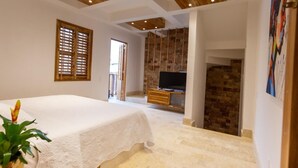 Une chambre à coucher avec un lit, une télévision, un plafond en bois et un mur en briques.