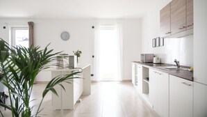 Une cuisine moderne avec des meubles blancs, un plan de travail en bois et une vue sur la salle à manger.