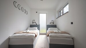 Une chambre d’hôtel moderne avec deux lits, une grande fenêtre et une porte donnant sur un balcon.