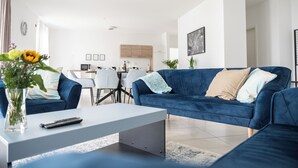 Un salon moderne avec un canapé bleu, une table basse blanche et un vase de fleurs.