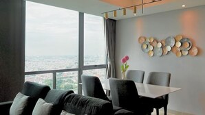A modern dining area with a large window, a dining table, and chairs. - Fairview House - Luxstay near Airport (Kelapa Dua)