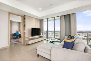 A modern living room with a large window, a flat-screen TV, a sofa, and a dining area. - Fairview House - Luxstay near Airport (Kelapa Dua)