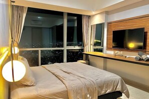 Ein modernes Hotelzimmer mit einem großen Bett, einem an der Wand montierten Fernseher und einem Fenster mit Vorhängen.