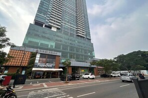 A tall building with a glass facade, a visible restaurant named 'PappaJack' at the ground level, and a parking area with cars.