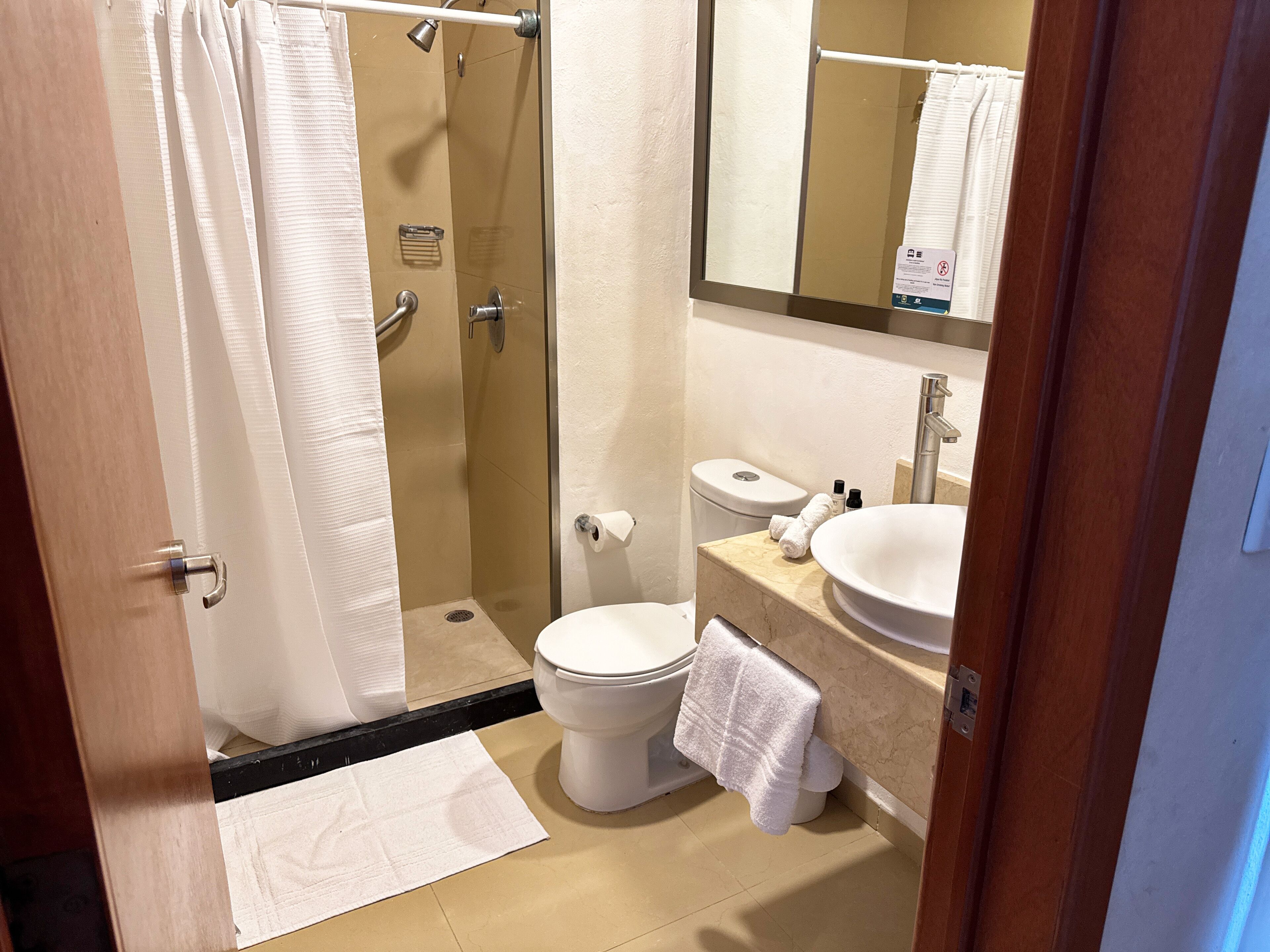A bathroom with a glass-enclosed shower, a toilet, a sink, and a mirror.