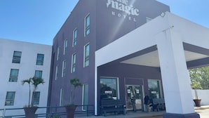 The Magic Hotels udvendige facade med moderne design, karakteriseret ved en lilla bygning, store vinduer og et overdækket indgangsparti.