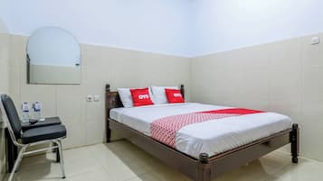 A neatly arranged hotel room with a bed, a chair, a desk, and a mirror.