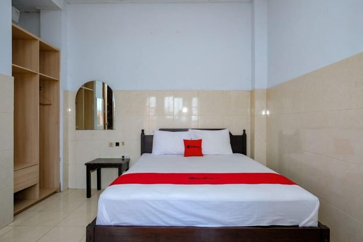 Una habitación de hotel con cama, mesita de noche, espejo y armario.