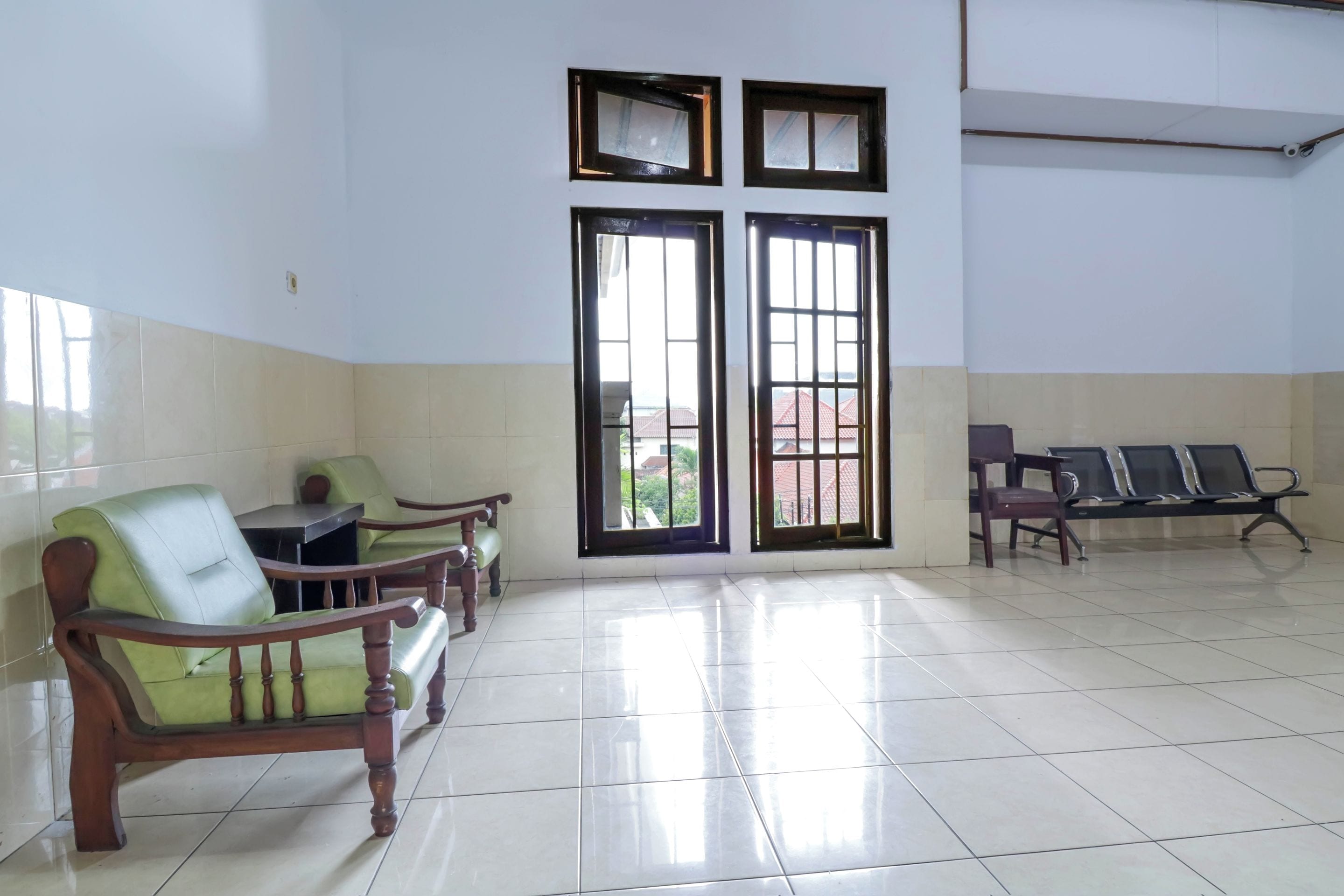 A waiting area with a tiled floor, wooden chairs, and a bench.