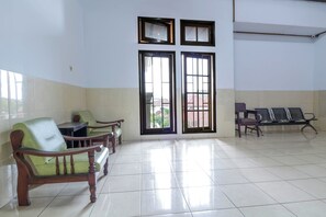 Un área de espera con suelo de baldosas, sillas de madera y un banco.