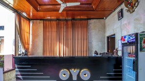 Una recepción con el nombre "OYO" bien visible, un ventilador de techo y un refrigerador lleno de bebidas.
