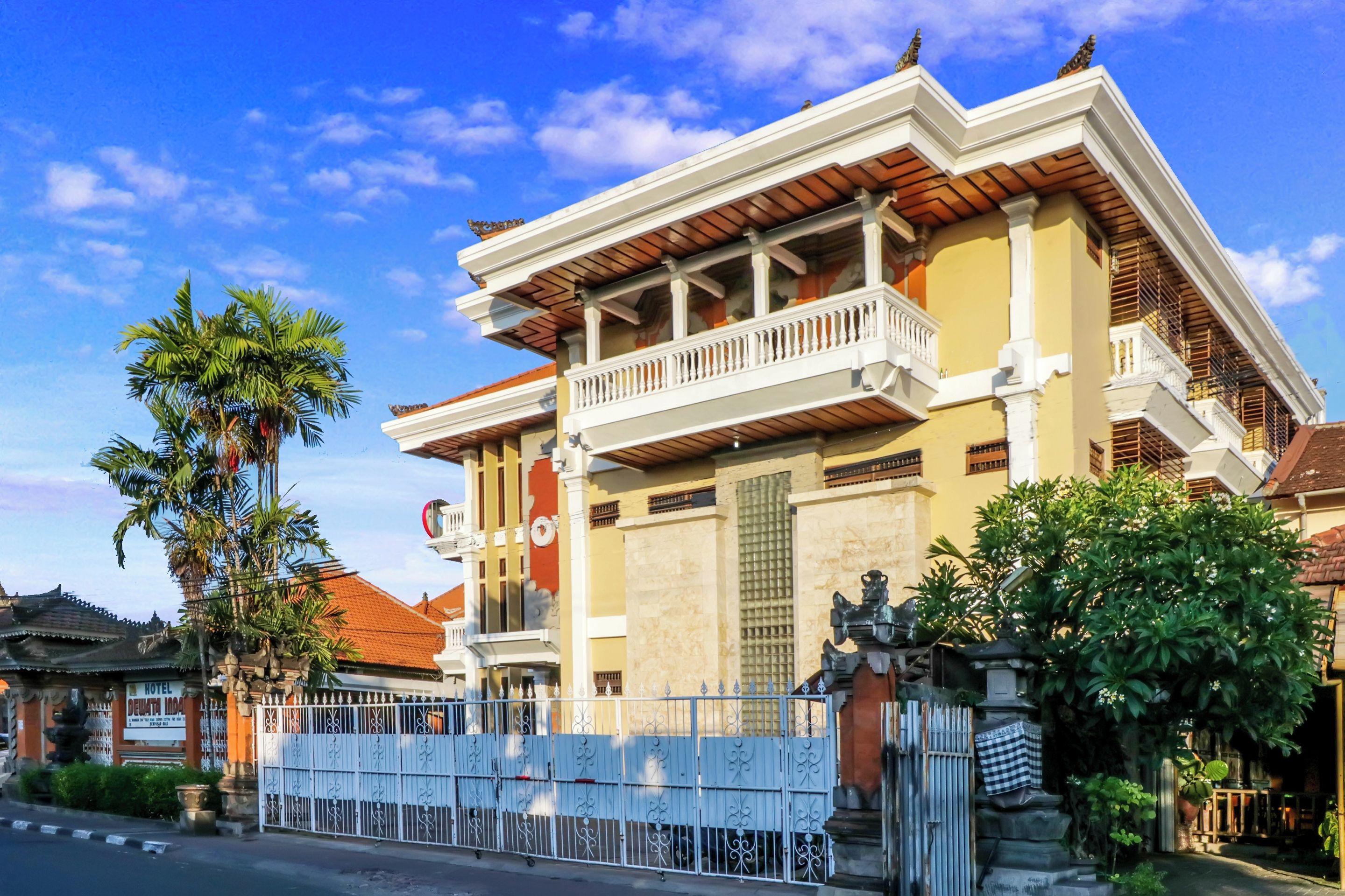 Un edificio tradizionale con un balcone, un cancello e una palma.