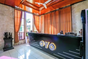 A reception desk with a sign reading 'OYO,' a ceiling fan, and a statue on the counter.