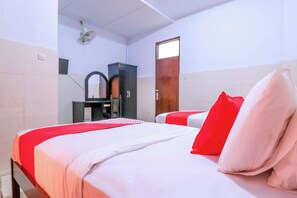 Habitación de hotel con dos camas, un armario de madera, un espejo y un ventilador de techo.