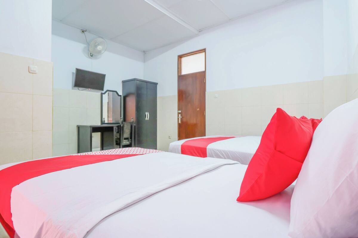 A hotel room with two beds, a television, a cabinet, and a door.