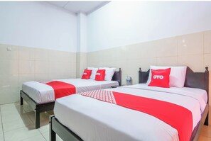 Habitación de hotel con dos camas, cada una con ropa blanca y detalles rojos, incluyendo almohadas y una colcha.