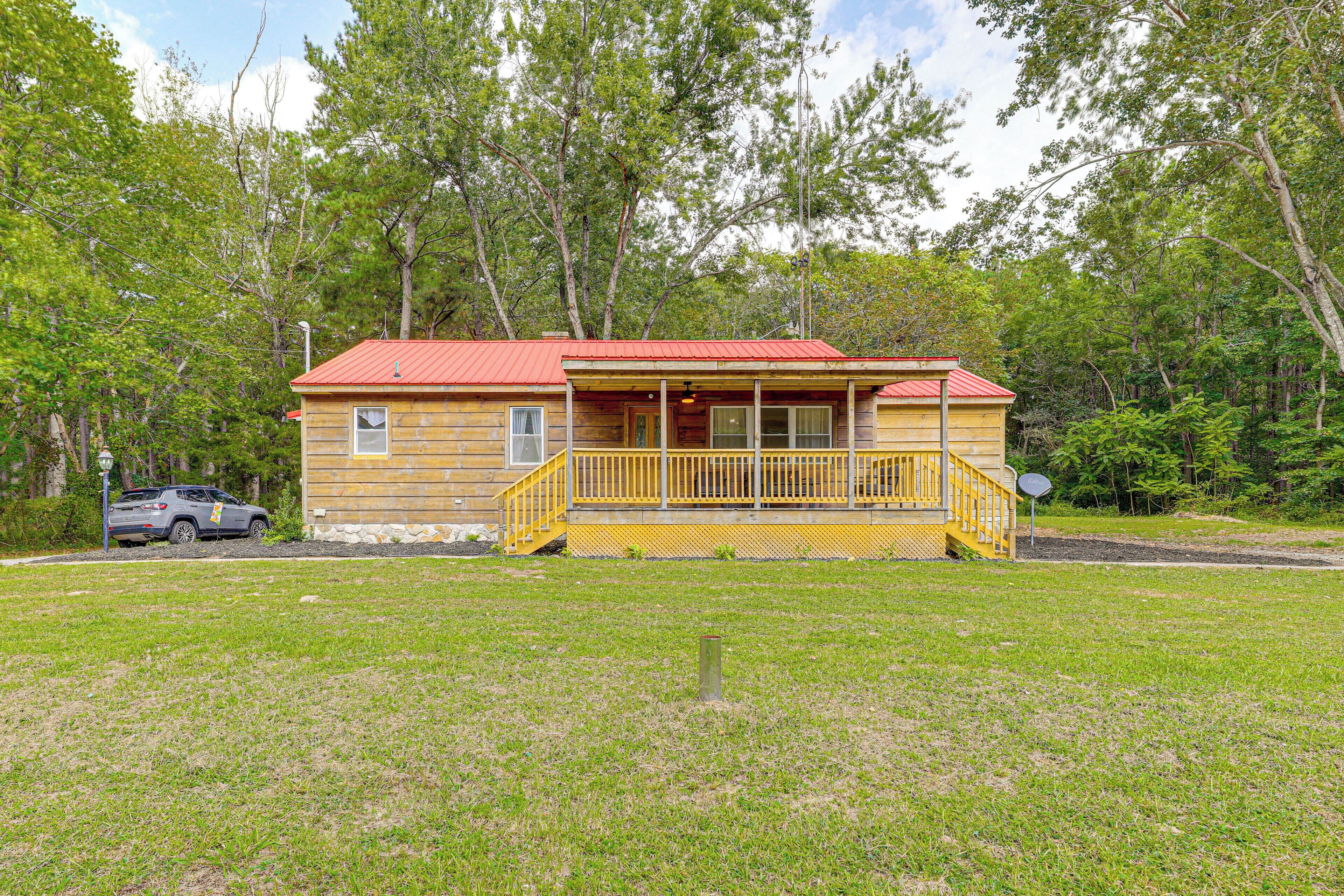 A wooden cabin with a red roof, a porch, and a small window.