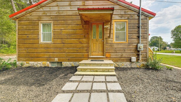 Une cabane en bois avec un toit rouge, une porte d’entrée et deux fenêtres.