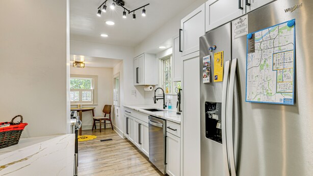 Una cocina moderna con electrodomésticos de acero inoxidable, armarios blancos y un mapa en el refrigerador.
