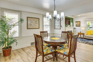A dining area with a round table, wooden chairs, and a potted plant.