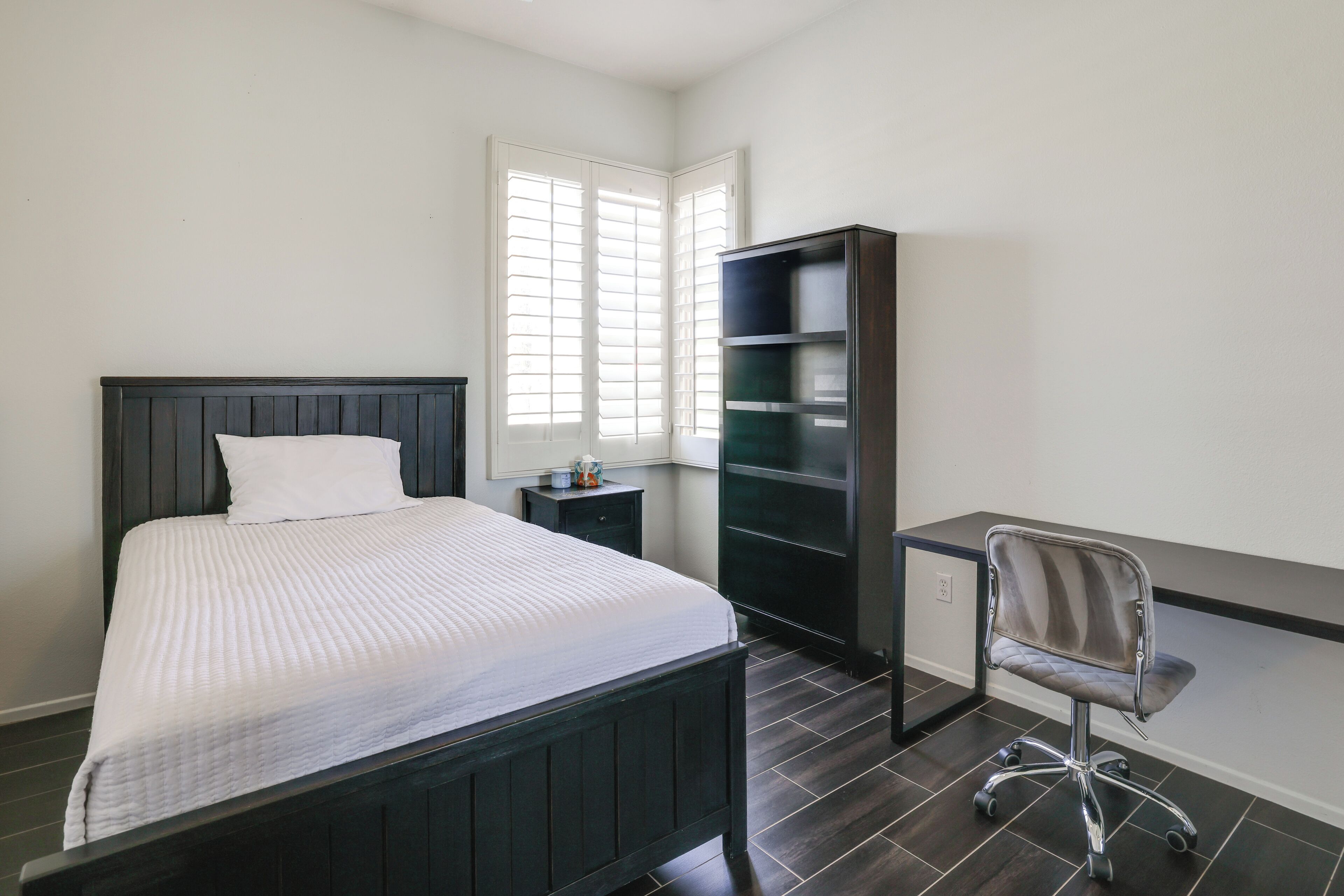 A bedroom with a bed, a desk, and a chair.