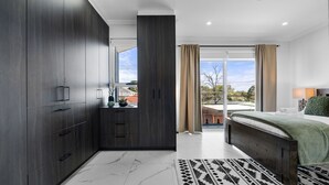 A modern bedroom with a large wardrobe, a bed with a green blanket, a patterned rug, and a view of the outdoors. - Spacious Lidcombe Lux mins to Sydney Olympic Park (Lidcombe)