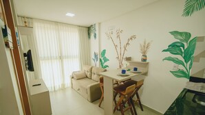 A compact living space with a sofa, a dining table with chairs, a small kitchen area, and decorative wall art. - Beach apartment on the Brazilian northeast coast - Maracaípe. (Ipojuca)
