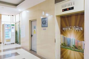 Een hotelgang met een automaat, een deur met de aanduiding 'GF' en een affiche dat 'SENTRA TIMUR RESIDENCE' promoot.