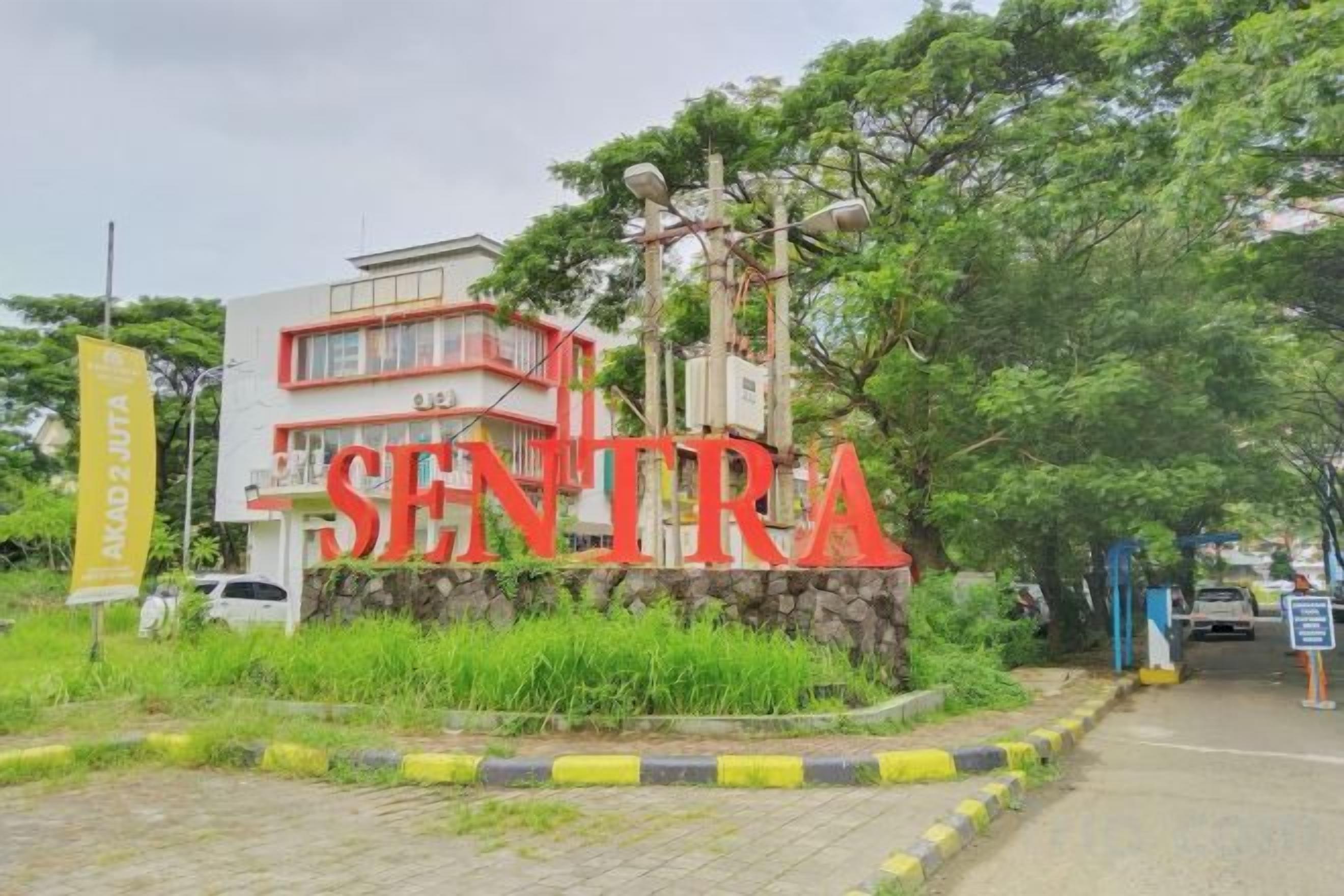 Um edifício com uma placa que diz 'SENTRA' e um muro de pedra à frente.