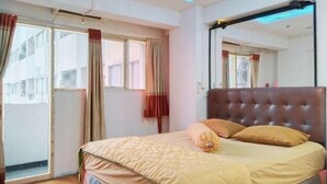 Een slaapkamer met een bed, gordijnen, een spiegel en uitzicht op het omliggende landschap.