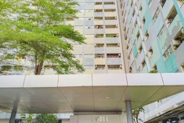 Un immeuble à plusieurs étages doté de balcons, d’une entrée couverte et d’un arbre au premier plan.