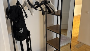 Ein Zimmer mit Holzboden, einem Metallgestell mit Kleidung und einem kleinen Holztisch.