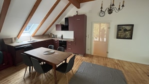 Eine Küche mit Holzbalken, einem Esstisch mit Stühlen, einer Kandelaber und einer Tür mit Blick.