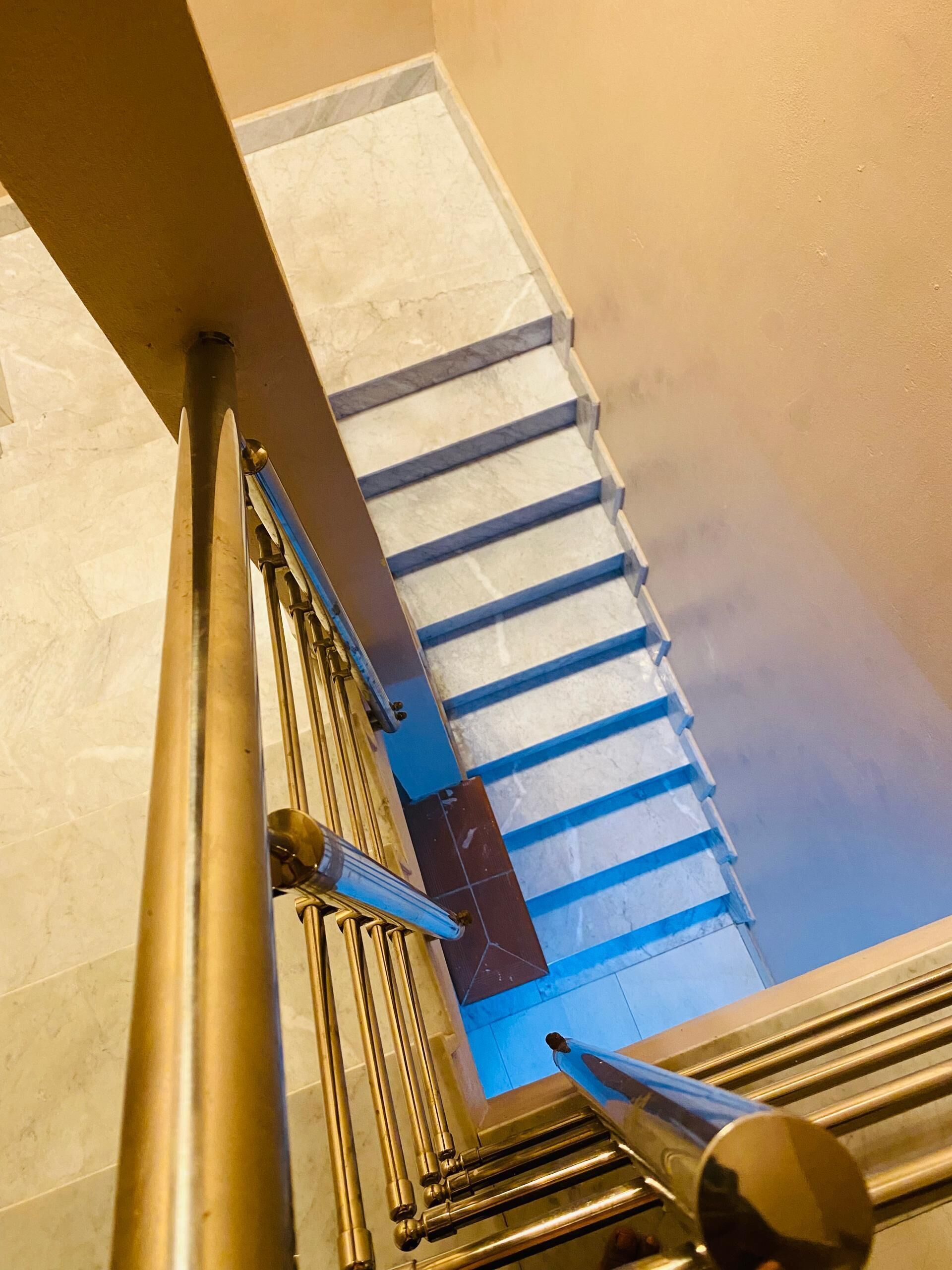 A staircase with marble steps and a blue handrail.