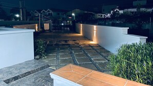 Eine Dachterrasse mit Steinböden, weißen Wänden und einem befestigten Eingang.