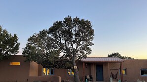 A modern building with a large tree in the center, stone pathways, and a hanging hammock. - Charming 3-bedroom/3 full bath home in lovely Santa Fe, private and peaceful (Santa Fe)