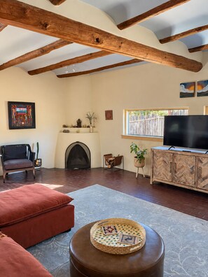 A living room with a fireplace, a television, and a herringbone-patterned cabinet.