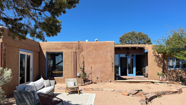 A modern building with a patio area featuring a sofa, chairs, and a rug. - Charming 3-bedroom/3 full bath home in lovely Santa Fe, private and peaceful (Santa Fe)