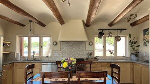 A kitchen with wooden beams, a dining table with chairs, a chandelier, and a view of the outdoors. - Charming 3-bedroom/3 full bath home in lovely Santa Fe, private and peaceful (Santa Fe)