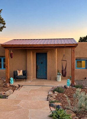A house with a blue door, a hanging chair, and a small garden.
