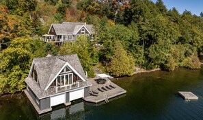 A house with a dock extending into a lake, surrounded by dense forest.