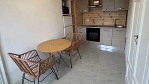 Una cucina con pavimento piastrellato, un tavolo rotondo con sedie e pensili in legno.