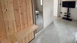 Una stanza con una porta scorrevole in legno, una televisione a schermo piatto e un pavimento piastrellato.