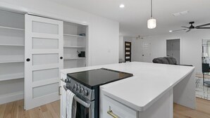 Une cuisine moderne dotée d’un îlot central, d’un four encastré et de meubles de rangement blancs.