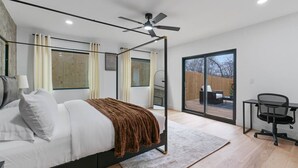 Une chambre moderne avec un lit à baldaquin, un bureau avec une chaise et une porte-fenêtre coulissante donnant sur un espace extérieur.