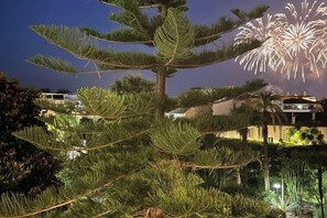 A tree with a complex structure, a building with lights, and fireworks in the background. - The Suite du Comte - Private Terrasse and Park View (Cannes)