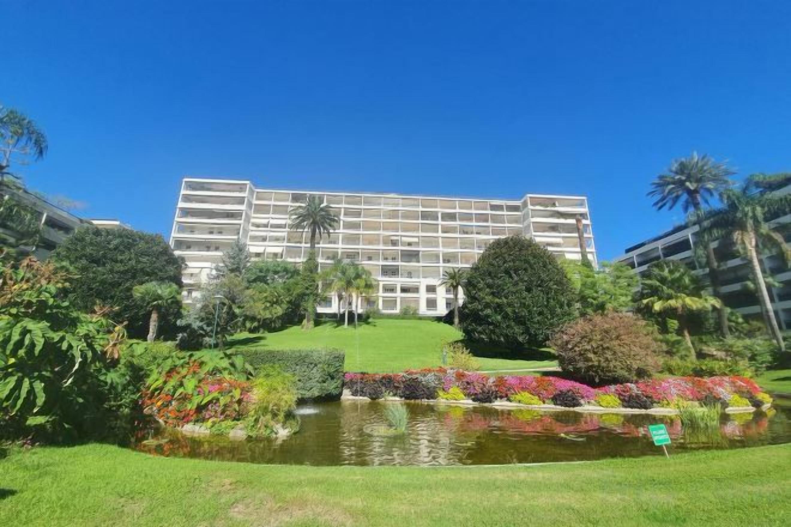 A hotel with a large building, a pond, and well-maintained gardens.