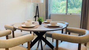 Un coin repas avec une table ronde, six chaises et une lampe.