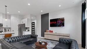 A modern living room with a sectional sofa, a coffee table, and a flat-screen TV mounted on the wall. - Mega Lux Combined Unit - Up to 36 Guests (Austin)